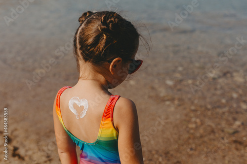 Little girl with heart shaped sunscreen on her back.