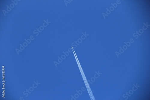 雲一つない青空を飛ぶ飛行機と、くっきり残る飛行機雲