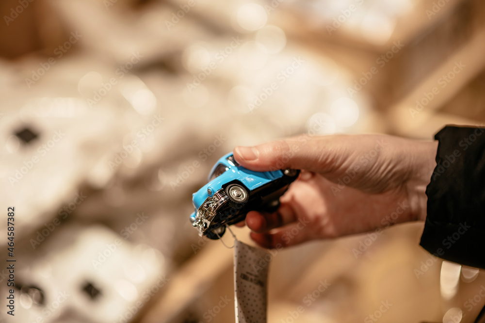 Fototapeta premium Man holding new small vintage blue toy car in hand - defocused background