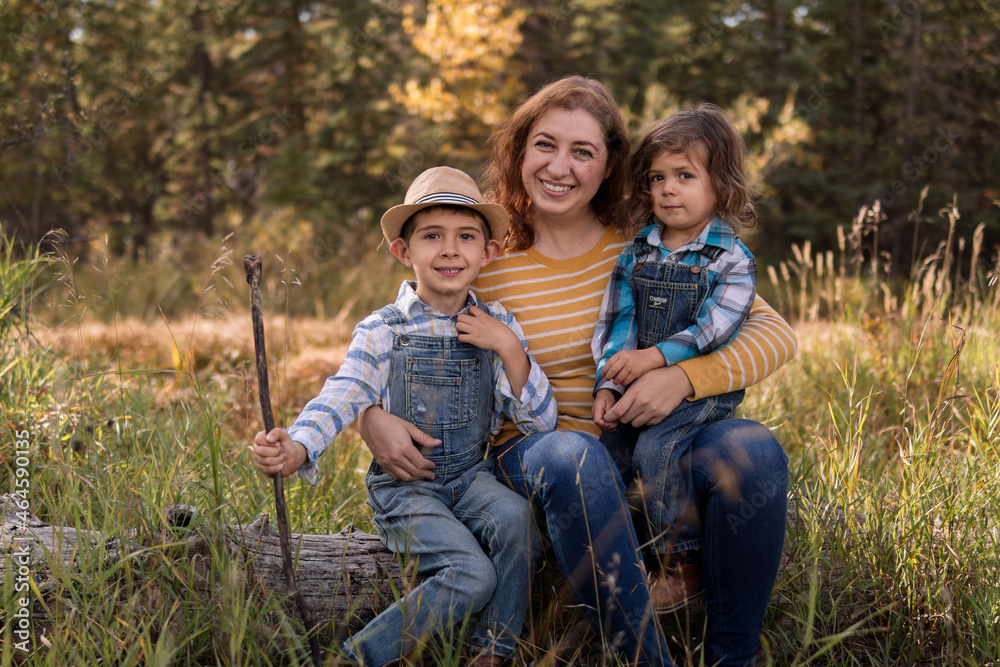 Fototapeta premium Parent and children sitting on a tree stump in a park
