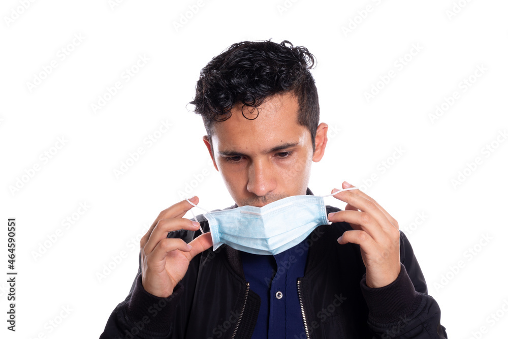 Man putting on a face mask. White background. Young adult about to put on face mask to protect himself from viruses. Man putting on a face mask. White background. Young adult about to put on face mask to protect himself from viruses.