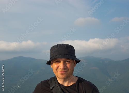 chest-high portrait of a man in a black panama hat against the background of mountains.