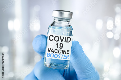Hand in blue medical gloves holding a vaccine vial with Covid 19 Vaccine Booster text, for Coronavirus booster shot Fototapet