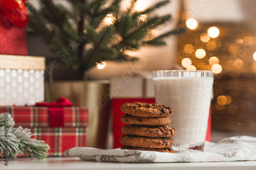 Merry Christmas 2022. Beautiful background with chocolate chip cookies and a glass of milk for Santa Claus. Celebrating the winter New Year holidays. The concept of the beginning of the year.