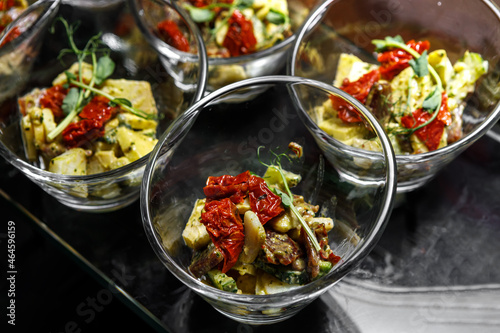 A light snack of potatoes, cucumbers, chili peppers, chicken meat and herbs in transparent serving cups.