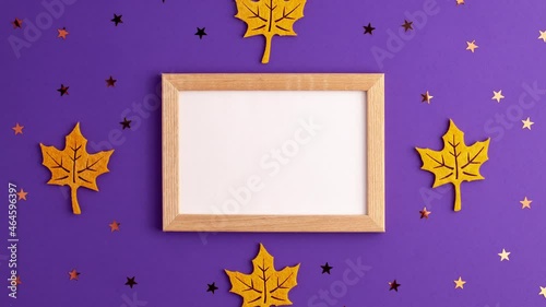 Stop motion animation of yellow felt autumn leaves star shapes and wooden picture frame on purple background with copy space. Halloween scary holiday and autumn concept