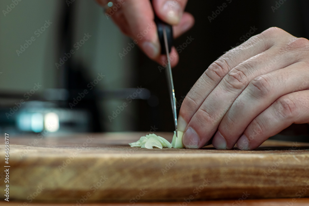 Chopping garlic on a wooden board for cooking. Copy space.