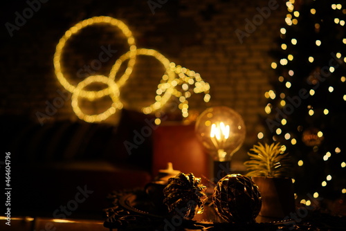 New Year 2021 interior with candles, bulbs and bokeh. Room decorated to christmas celebration. Christmas tree with presents 