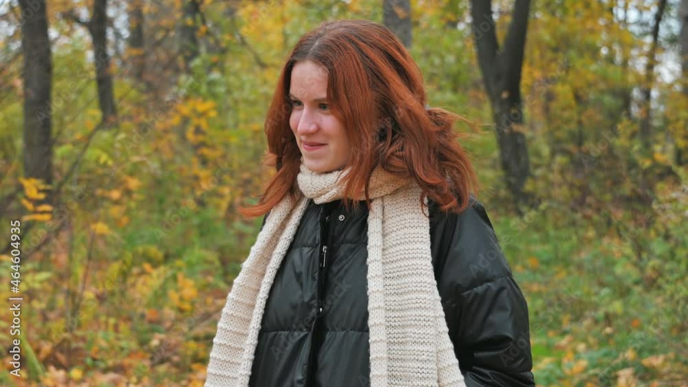a young red-haired girl is talking to someone in an autumn yellow park. a young red-haired girl is talking to someone in an autumn yellow park.