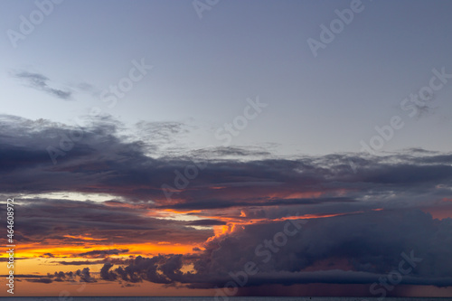 lever de soleil dessus de l'océan avec un ciel orangé et des nuages avec lueur orange © Veronique