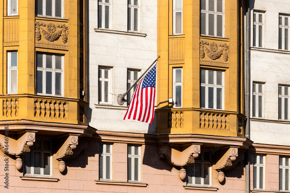Obraz premium National flag of USA on a flagpole waving against a background of historical building