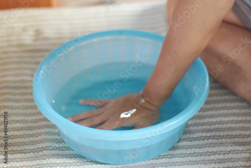 First aid therapy for Trigger finger disease concept. Hand of people soak your hands in warm water in blue bowl color to relax inflamed muscles and treat the pain from Trigger finger disease.