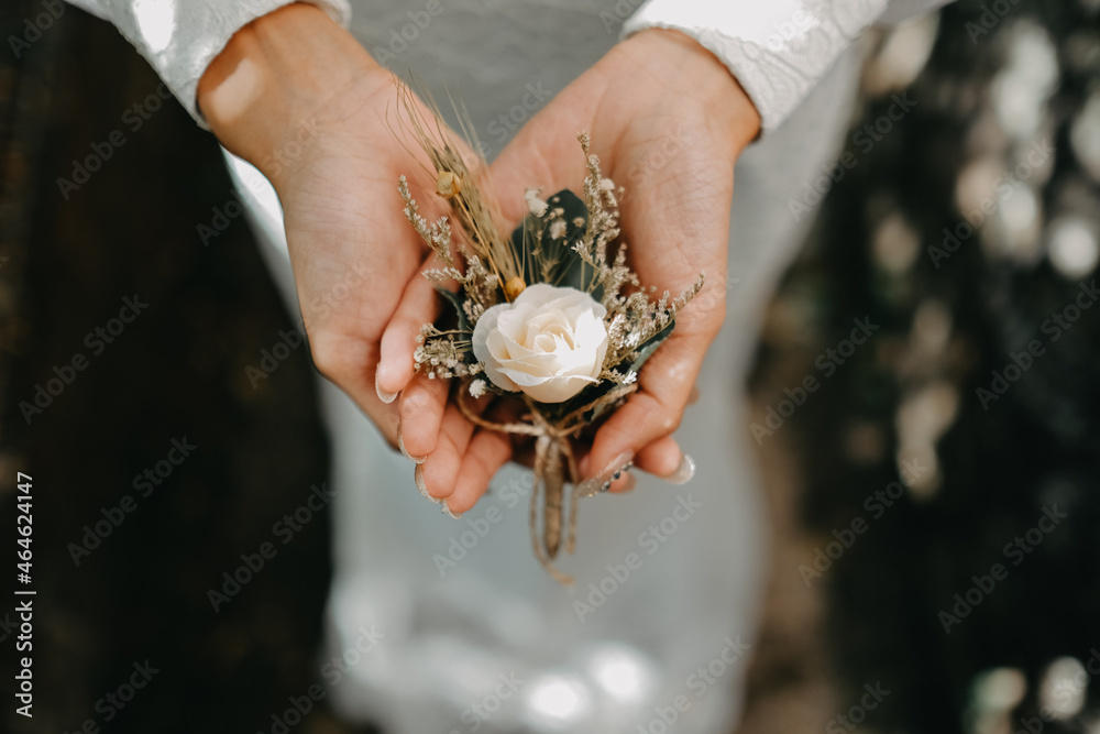 bride in white holding wedding flower corsage in her hand during her wedding day