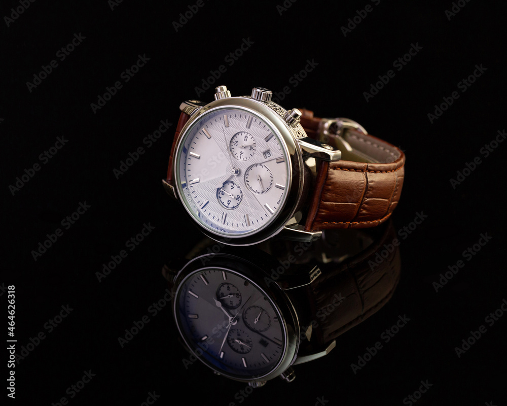 Unbranded hand watch with brown leather strap on black glassy surface, closeup. Product photography and shopping concept Unbranded hand watch with brown leather strap on black glassy surface, closeup. Product photography and shopping concept