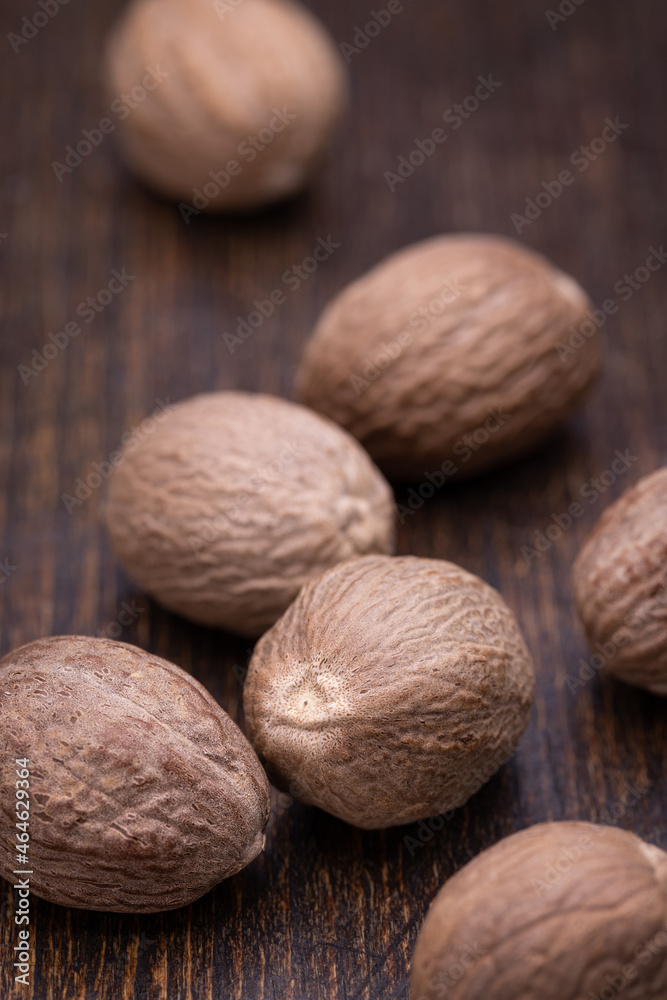 Whole nutmegs on a wooden brown background. Close-up, vertical shot. Whole nutmegs on a wooden brown background. Close-up, vertical shot.