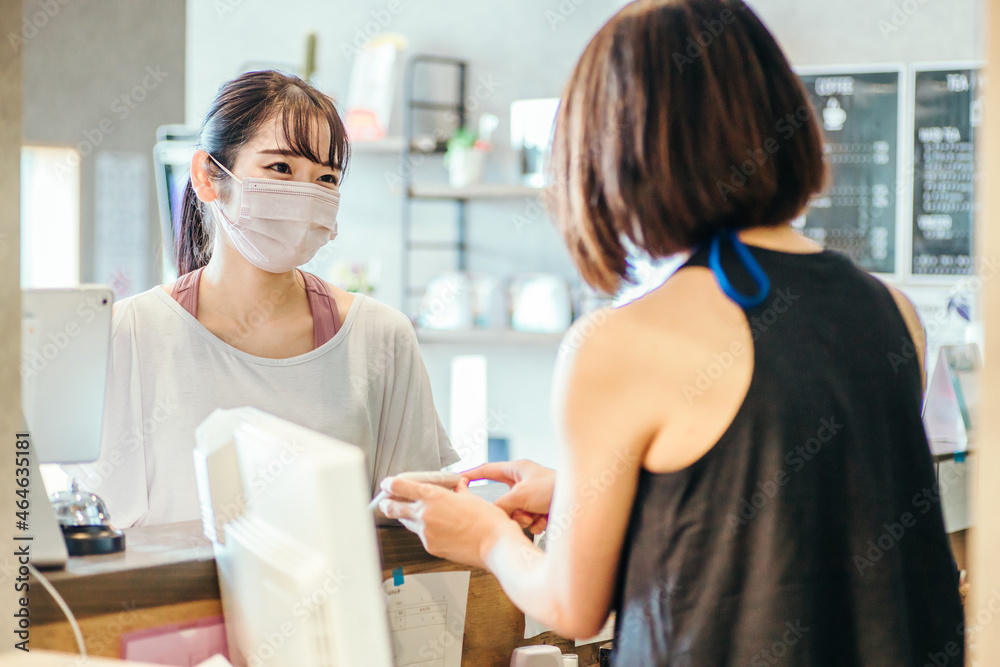 Obraz premium 受付でスマホを出す女性（マスク） 