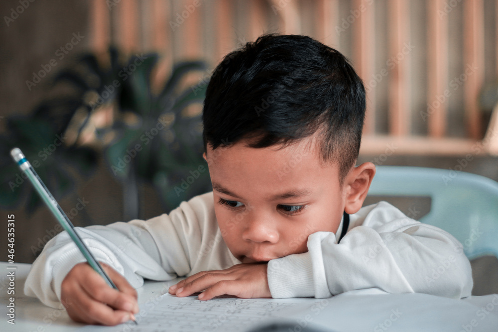 Child boy holding pencil writing. Asian Boy doing homework, kid writing paper, education concept, back to school. Child boy holding pencil writing. Asian Boy doing homework, kid writing paper, education concept, back to school.