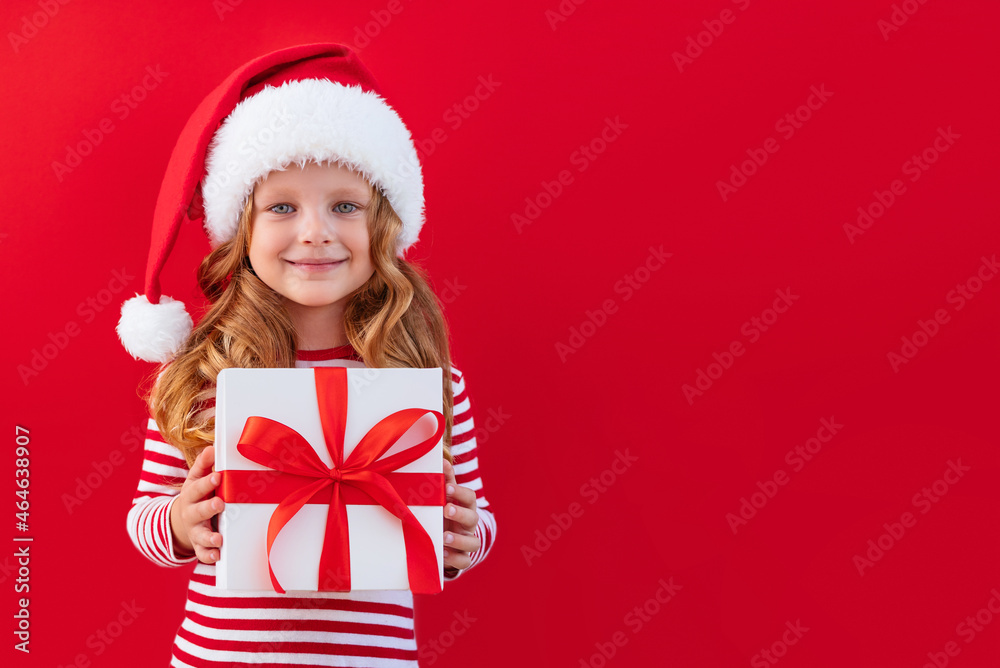 Christmas banner child in a santa hat holding a gift on a red background with place for text Christmas banner child in a santa hat holding a gift on a red background with place for text