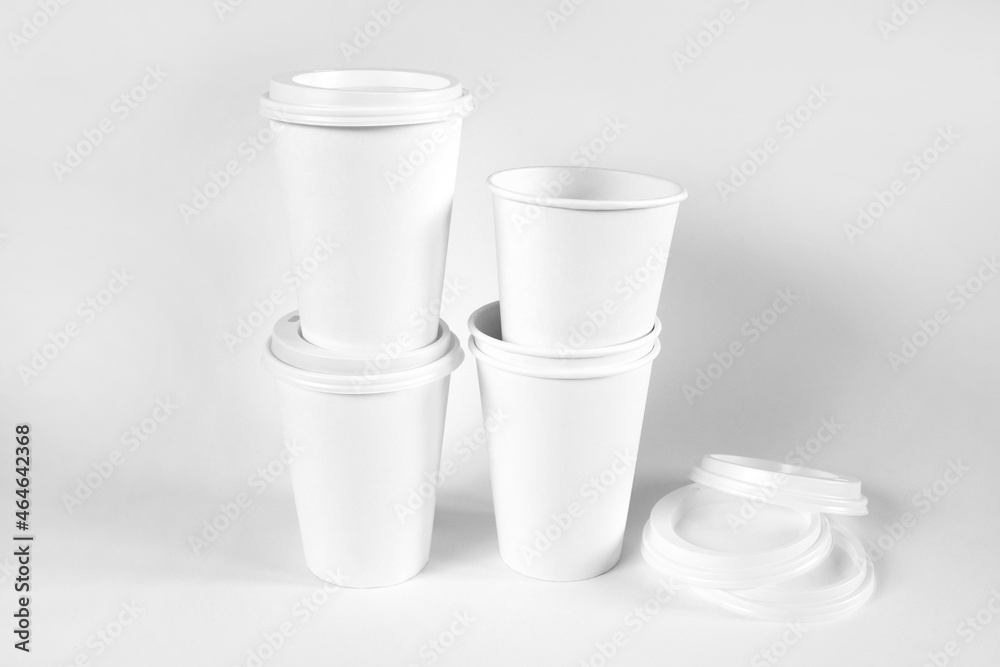 Paper coffee cups with white lids on white backgrounds. Open and closed paper cup. Realistic vector mockup. White cups mock up