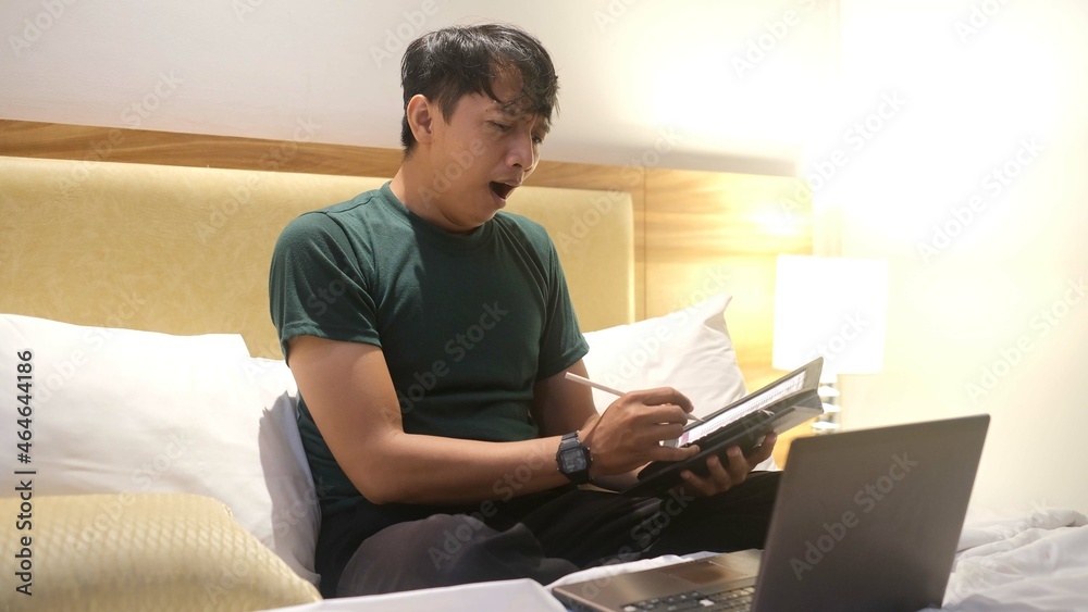 Surprised Asian man working with his laptop on his bed. Freelance problem concept. Surprised Asian man working with his laptop on his bed. Freelance problem concept.