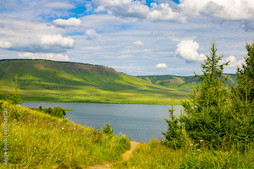 Landscape. Lake from a height among the green mountains against the backdrop of a cloudy sky. Lake Maloe, Siberia, Krasnoyarsk Territory, Russia, panoramic photo.