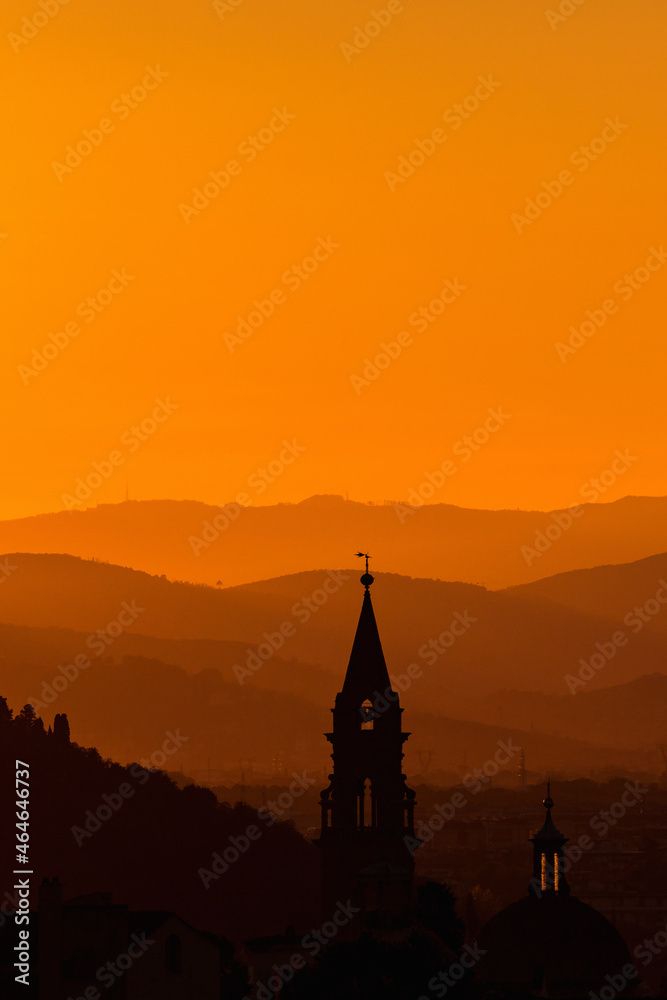 Obraz premium Church tower in the sunset silhouette with mountains in the background