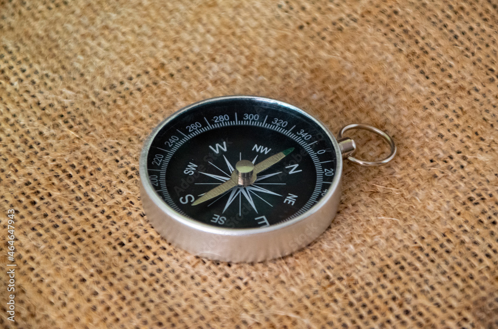 Compass on burlap. Geographical background close-up. Tourism, geography, path, direction Compass on burlap. Geographical background close-up. Tourism, geography, path, direction