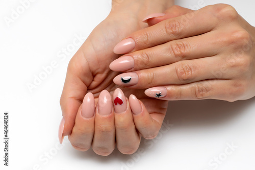 Beige  natural  natural  nude manicure with painted black moon  stars and red heart on long oval nails close-up on a white background.