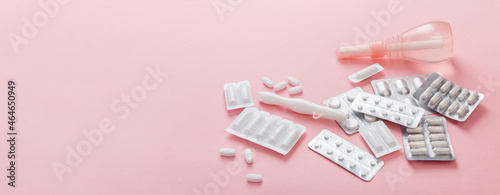 Gynecology concept banner. Vaginal suppositories, enema, tablets, applicator on pink background, treatment of vaginal infections from candidiasis, thrush, sexually transmitted infections. Woman health photo