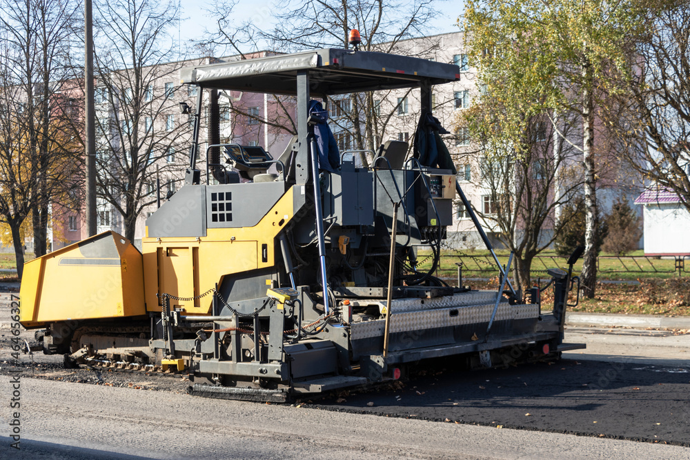 An asphalt paving machine works in the city center in the fall. Repair of road surfaces in a modern city using specialized equipment.