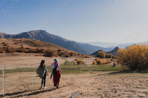 two women tourists are walking along the road among the hills and mountains