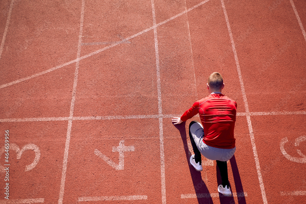 top view of young adult male athlete in low start position at athletic  track. start line position. copy space Stock Photo