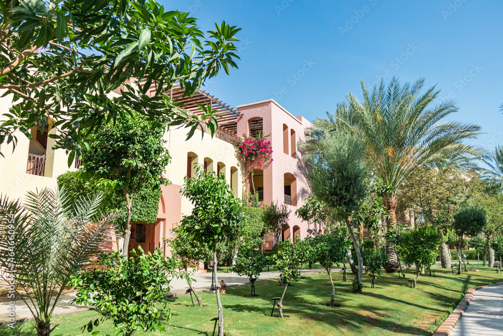 Yellow orange bright building among green tropical garden on a sunny day