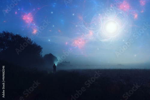 An alien invasion concept. Of glowing UFO's in the night sky with a figure looking up on a misty spooky night.