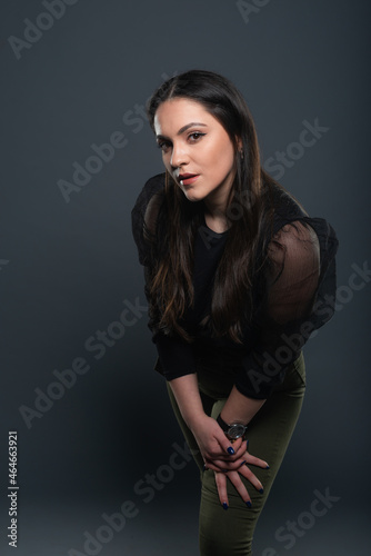 Portrait of beautiful model in black dress  hat and sunglasses on gray background