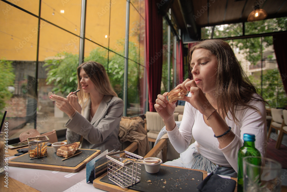 One girl is eating while the other is fixing her make up One girl is eating while the other is fixing her make up