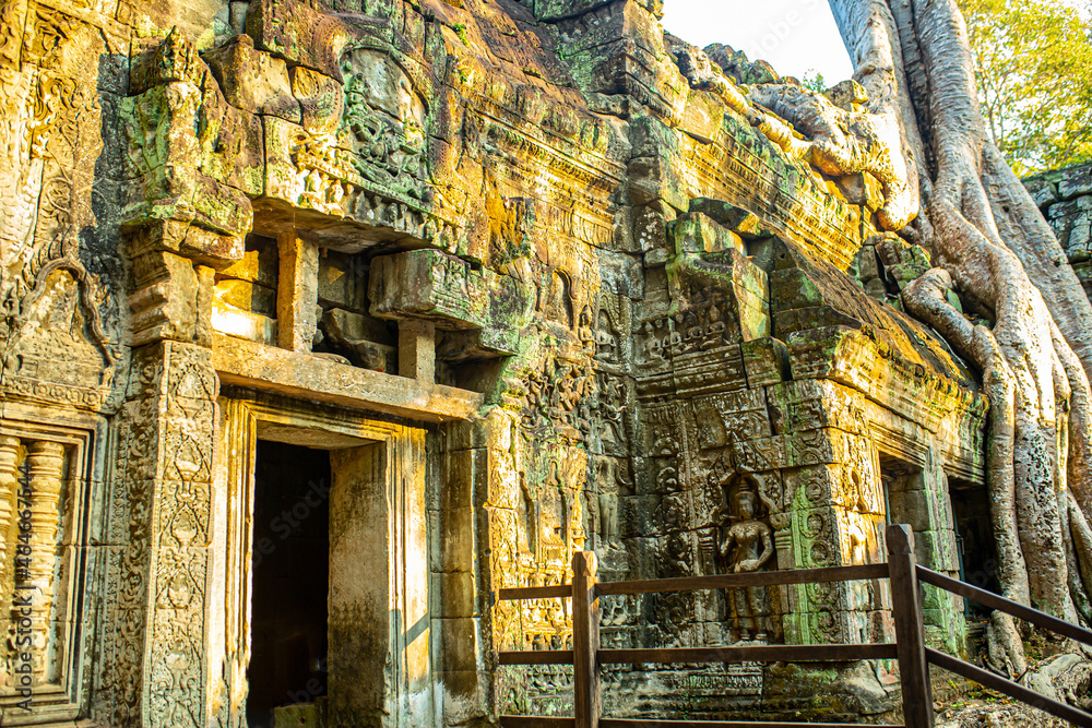 Fototapeta premium The ancient city of Angkor Wat in Cambodia. Towers of the temple of the Kmer people streets and ruins of houses. Traveling to the sights of ancient civilizations. Stone bas-reliefs on the ruins.