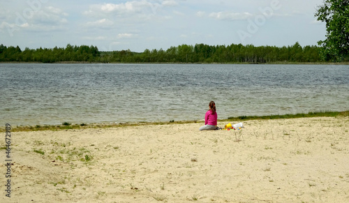 Plaża i dziewczynka siedząca na piasku. 