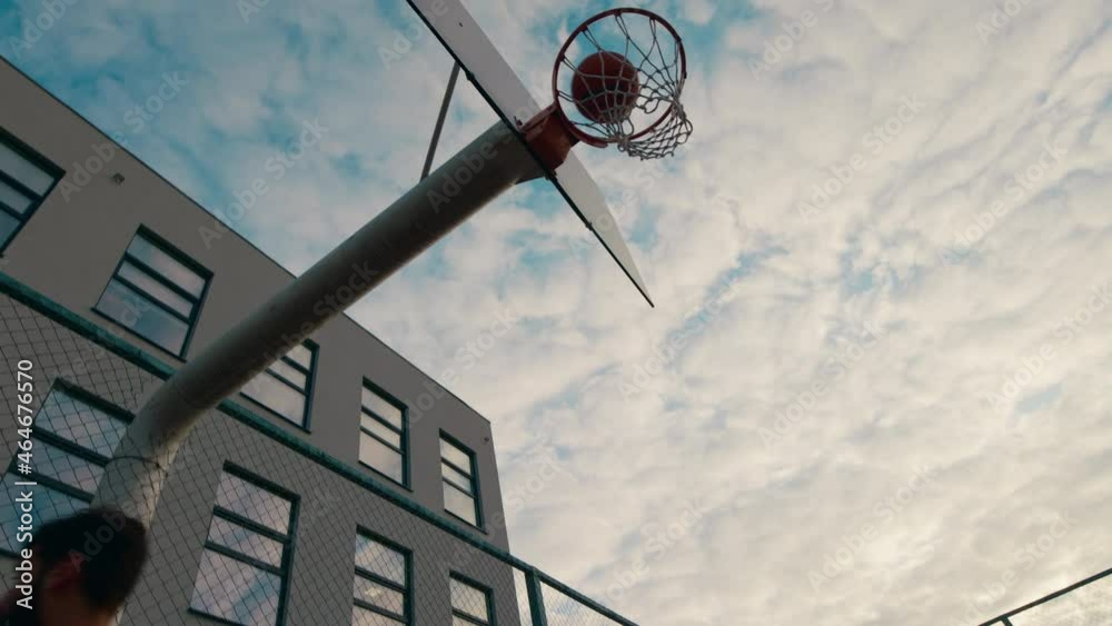 Charismatic man in a red sport suit playing basketball he throw the ball in the basket in a large stadium Charismatic man in a red sport suit playing basketball he throw the ball in the basket in a large stadium