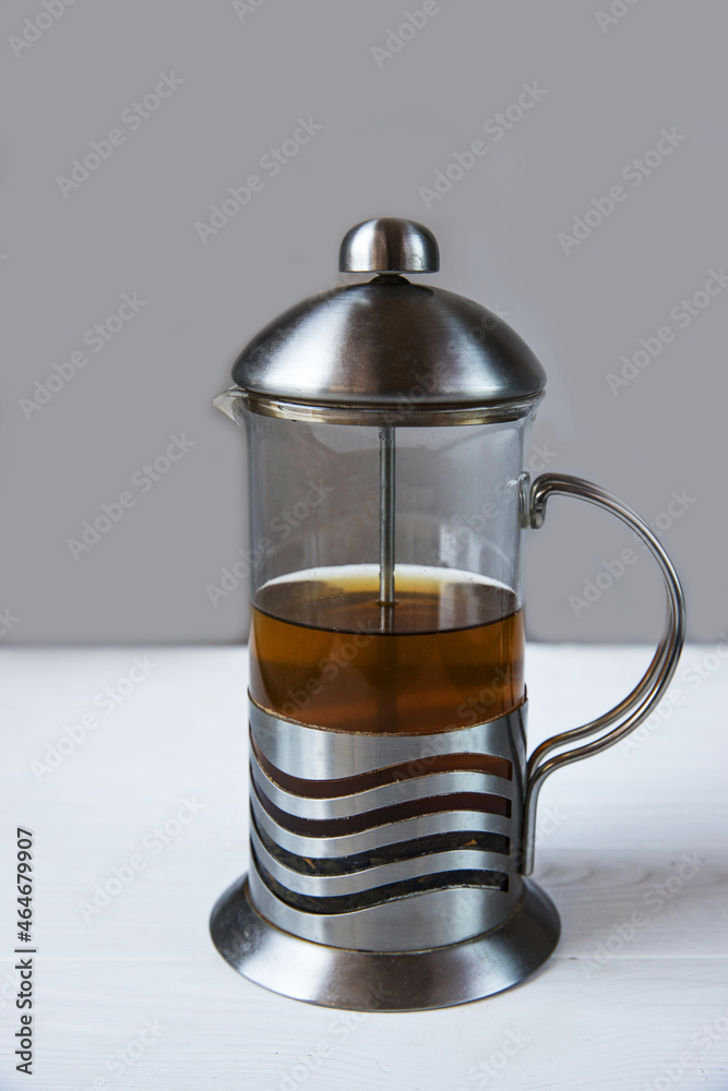 glass teapot and cup/ Male hands hold a lemon over a green cup of tea on the background of a white wooden table. Hot drink with vitamin C. Treatment of colds with lemon tea. glass teapot and cup/ Male hands hold a lemon over a green cup of tea on the background of a white wooden table. Hot drink with vitamin C. Treatment of colds with lemon tea.
