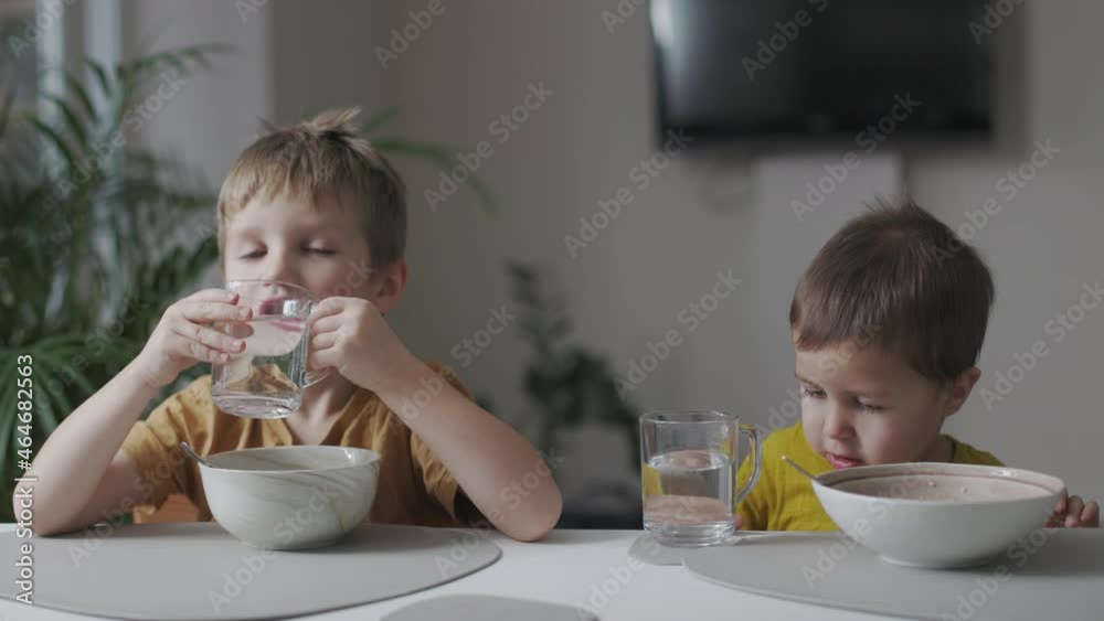 Breakfast in the home kitchen. Portrait of two little kids eating healthy porridge. Breakfast in the home kitchen. Portrait of two little kids eating healthy porridge.
