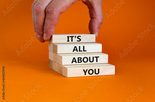 It is all about you symbol. Wooden blocks with words 'It is all about you'. Beautiful orange background. Businessman hand. Copy space. Business and it is all about you concept. photo