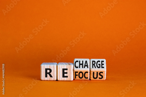 Refocus and recharge symbol. Businessman turned cubes and changed the word 'refocus' to 'recharge'. Beautiful orange table, orange background. Business refocus and recharge concept. Copy space.