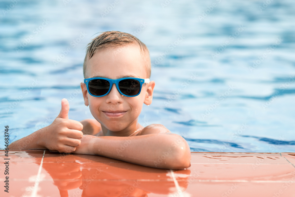 Boy in sunglasses in the pool. Summer vacation of a child in the pool.