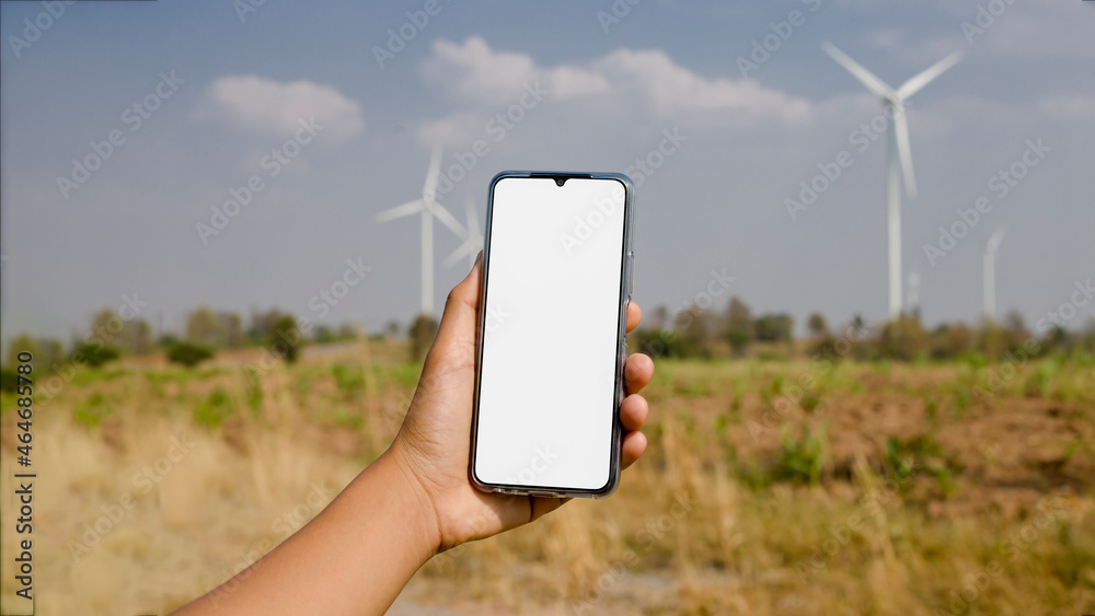 A smartphone with a creative white screen and a field of electric wind turbines in the background.