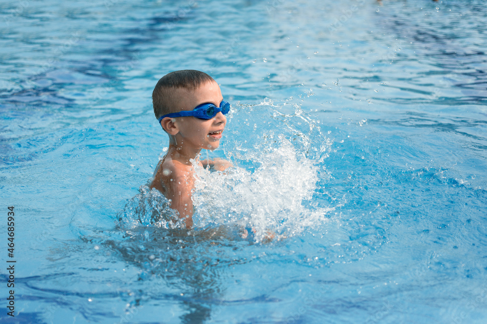 child in pool. Boy in blue goggles for swimming in the pool. Summer vacation of a child in the pool.