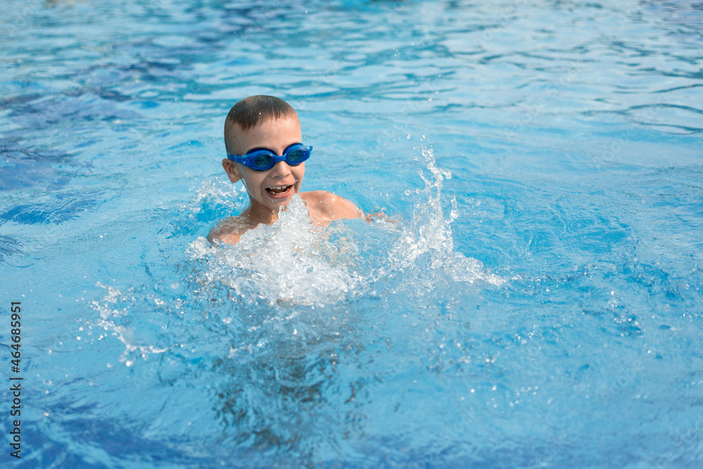 boy swimming in the pool. Boy in blue goggles for swimming in the pool. Summer vacation of a child in the pool.
