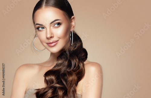 Beautiful girl . Fashionable and stylish woman in trendy jewelry big earrings .Curly ponytail hairstyle. Fashion look , beauty and style. Natural makeup and cosmetics