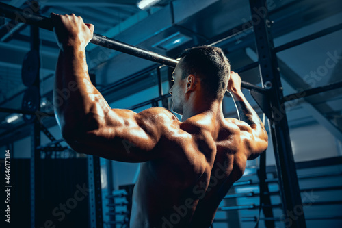 Portrait of muscled athlete, bodybuilder workouts alone at sport gym, indoors. Concept of sport, activity, healthy lifestyle photo