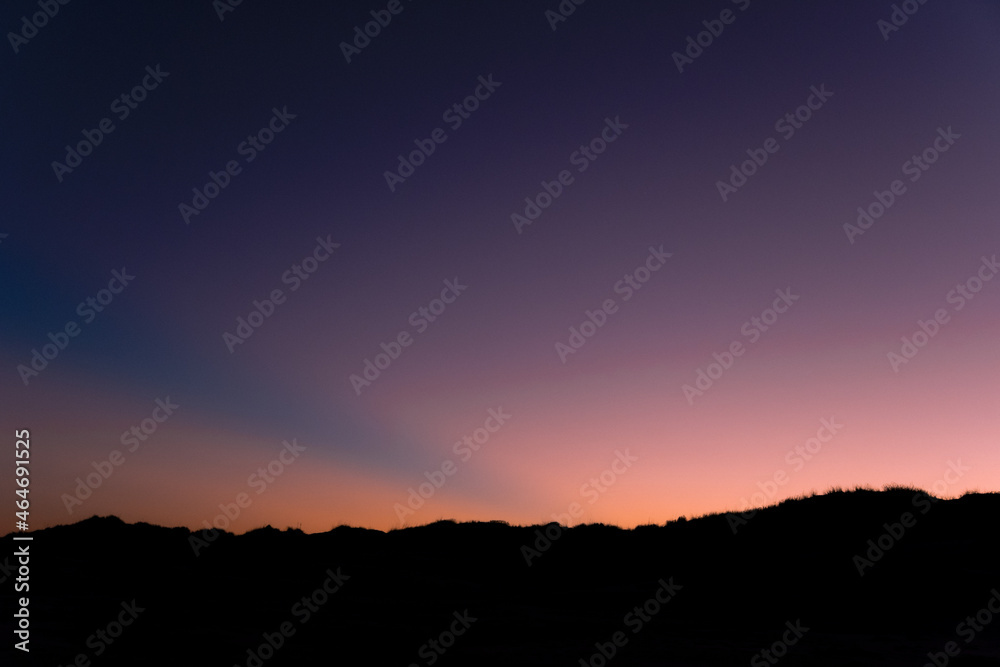 colorful purple and salmon-colored sky  with the silhouette of a beach
